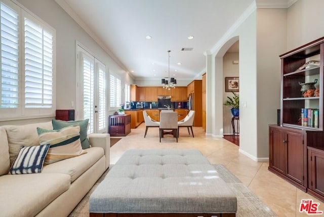 living room with light tile patterned flooring, ornamental molding, and a chandelier