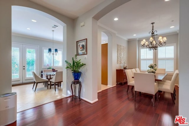 dining space with dark hardwood / wood-style flooring, crown molding, a healthy amount of sunlight, and an inviting chandelier