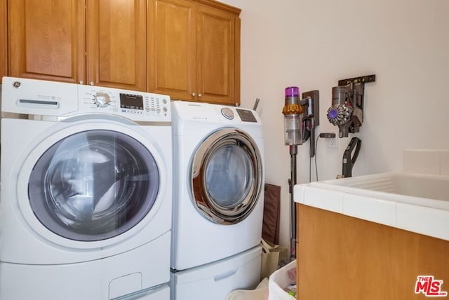 clothes washing area featuring washer and clothes dryer and cabinets