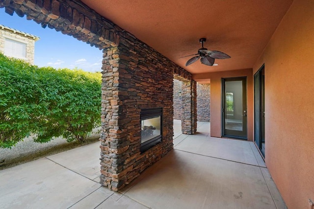 view of patio with ceiling fan and an outdoor stone fireplace