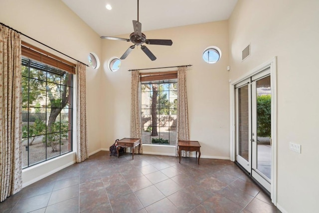 unfurnished room featuring ceiling fan, dark tile patterned floors, and a high ceiling