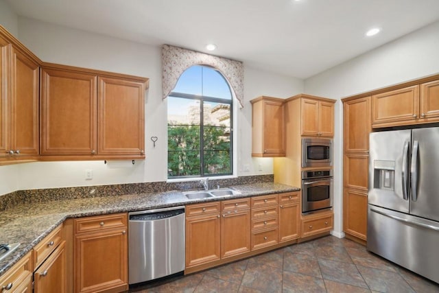 kitchen with sink, stainless steel appliances, and dark stone counters