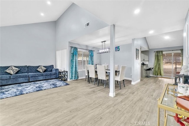 dining space featuring lofted ceiling, a chandelier, visible vents, baseboards, and light wood finished floors