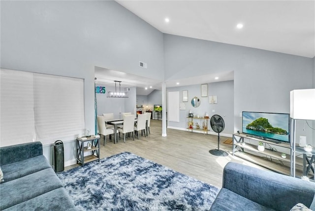 living area featuring recessed lighting, visible vents, wood finished floors, high vaulted ceiling, and baseboards