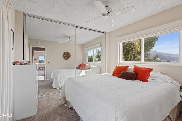 carpeted bedroom featuring a closet, a textured ceiling, and a ceiling fan