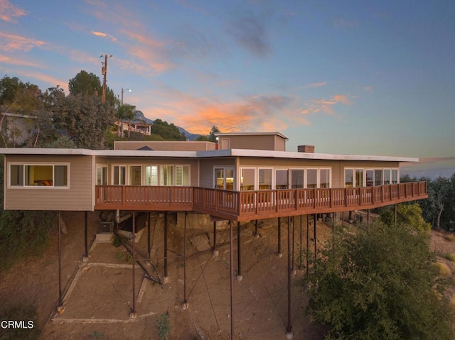 back of house at dusk featuring a wooden deck