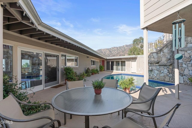 view of patio with an outdoor pool, outdoor dining area, and a mountain view