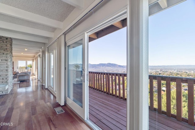 interior space with visible vents, hardwood / wood-style floors, beam ceiling, a mountain view, and a textured ceiling