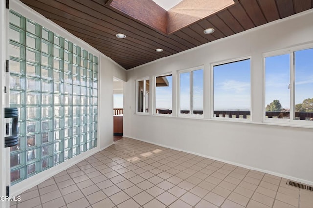 tiled spare room with visible vents, baseboards, and wooden ceiling