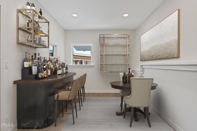 bar featuring wood finished floors, a dry bar, recessed lighting, and baseboards