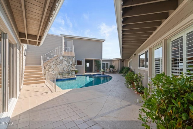 outdoor pool featuring stairway and a patio