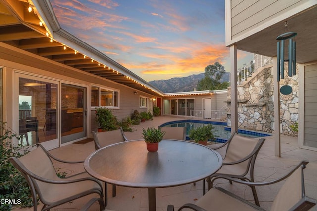 view of patio / terrace featuring outdoor dining space, an outdoor pool, and a mountain view