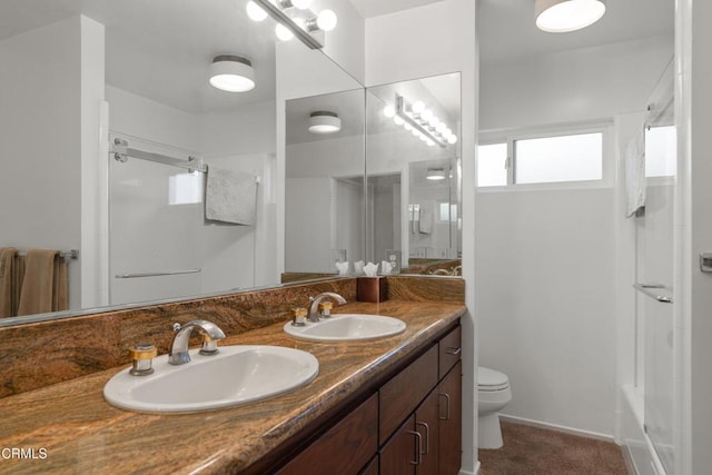 full bathroom featuring double vanity, toilet, walk in shower, and a sink