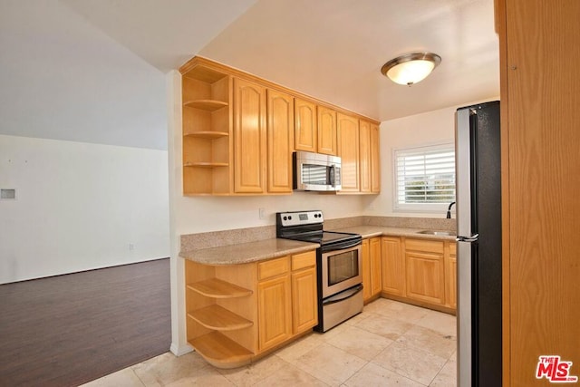 kitchen with stainless steel appliances, sink, light tile patterned floors, and light brown cabinetry