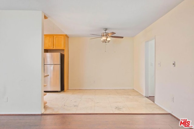 interior space with ceiling fan, stainless steel fridge, light brown cabinetry, and light hardwood / wood-style floors