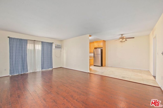 unfurnished room with a wall mounted AC, ceiling fan, and light hardwood / wood-style flooring