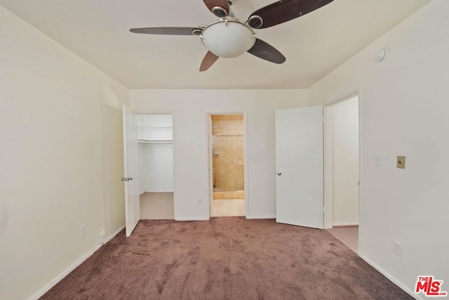 unfurnished bedroom featuring ensuite bathroom, a spacious closet, light colored carpet, a closet, and ceiling fan