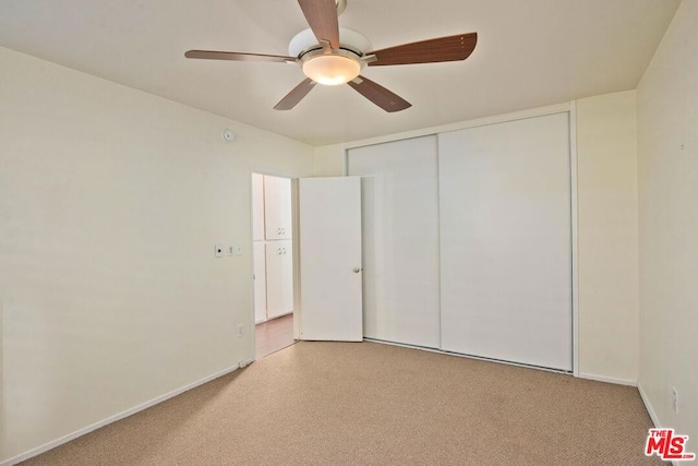 unfurnished bedroom with light carpet, ceiling fan, and a closet