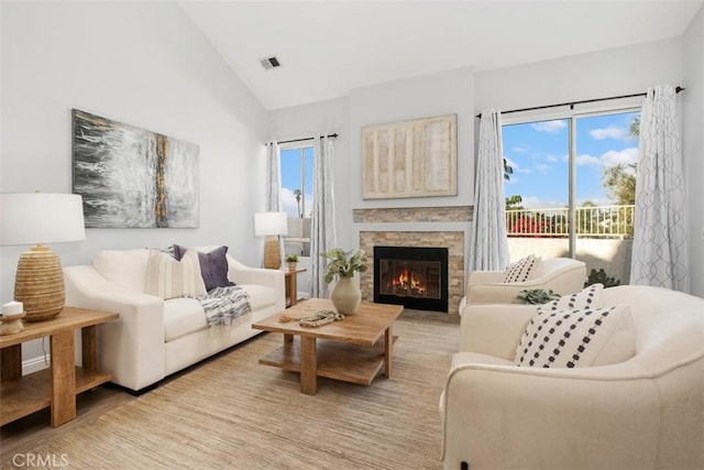 living room featuring a stone fireplace and vaulted ceiling