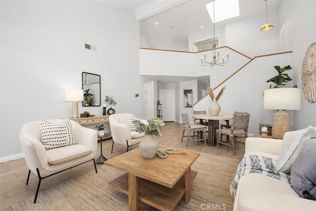 living room with a notable chandelier, beam ceiling, a skylight, and a high ceiling