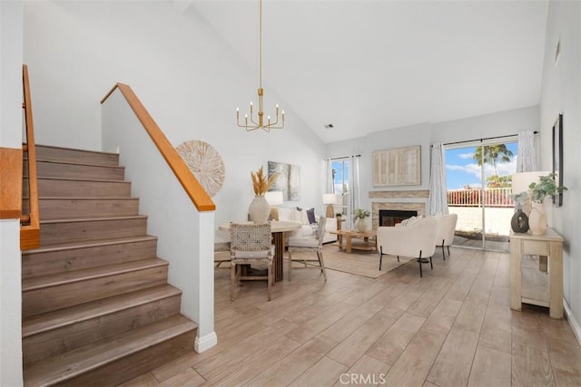 living room with an inviting chandelier, high vaulted ceiling, and light hardwood / wood-style flooring