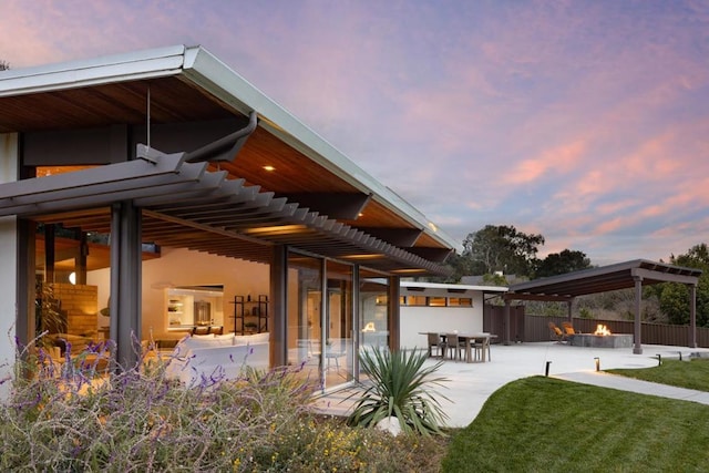 back house at dusk with a bar, a fire pit, and a patio area