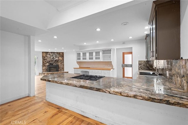 kitchen featuring sink, backsplash, white cabinets, kitchen peninsula, and stainless steel gas stovetop