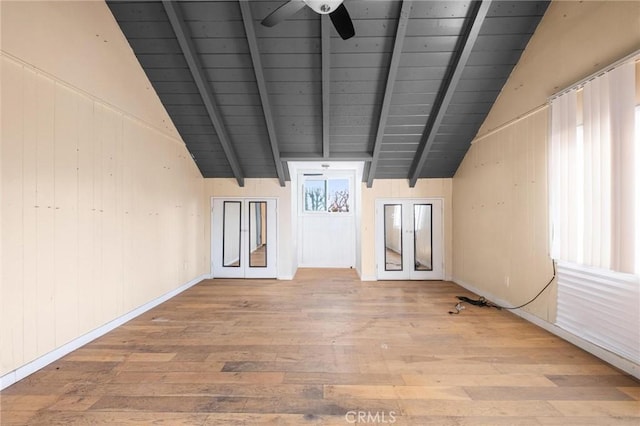 unfurnished room with hardwood / wood-style floors, wood walls, lofted ceiling with beams, wood ceiling, and french doors