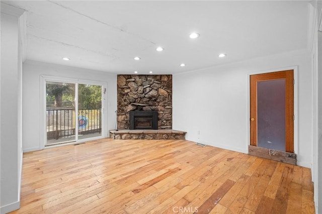 unfurnished living room featuring a fireplace, ornamental molding, and light wood-type flooring