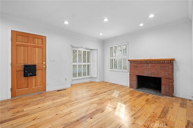 unfurnished living room with crown molding, light hardwood / wood-style floors, and a brick fireplace