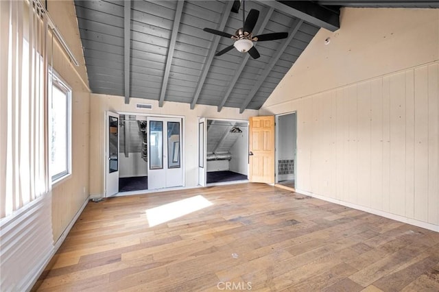 unfurnished room with vaulted ceiling with beams, wood ceiling, light hardwood / wood-style flooring, wooden walls, and ceiling fan