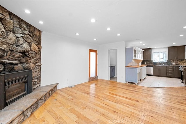 living room featuring a stone fireplace, sink, and light wood-type flooring