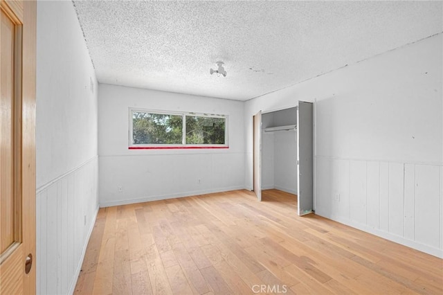 unfurnished bedroom featuring a closet, light hardwood / wood-style floors, and a textured ceiling