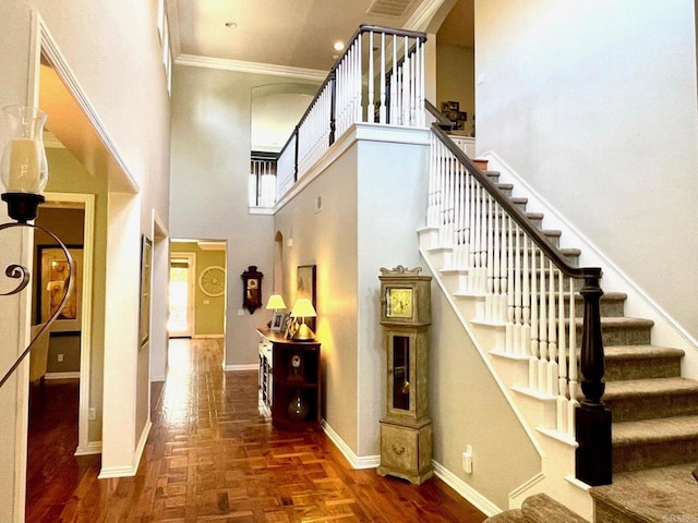 stairs featuring a towering ceiling, parquet floors, baseboards, and crown molding