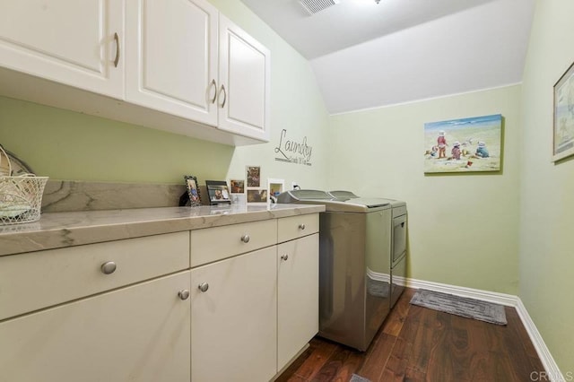 clothes washing area featuring dark wood finished floors, washing machine and dryer, cabinet space, and baseboards