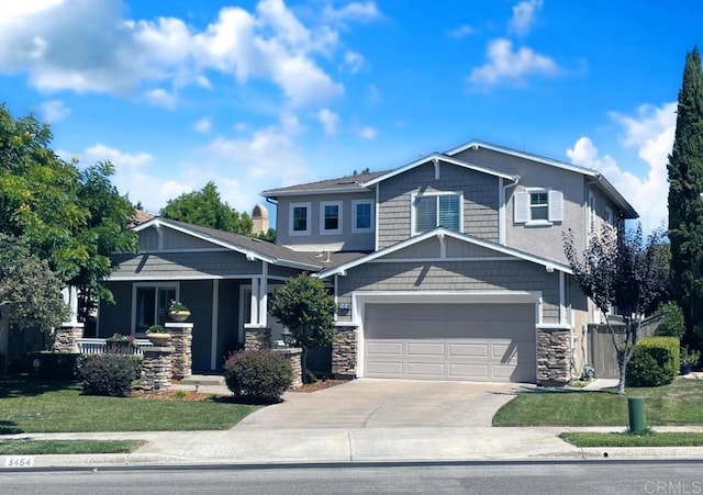 craftsman-style house featuring a garage, concrete driveway, a front lawn, and stone siding