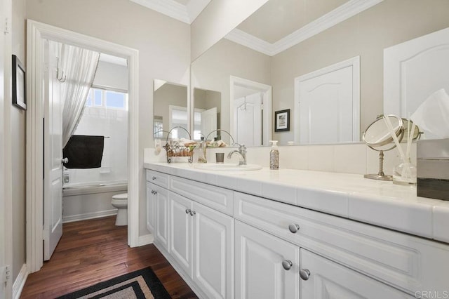 bathroom featuring toilet, wood finished floors, vanity, washtub / shower combination, and crown molding