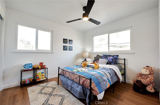 bedroom featuring multiple windows, wood-type flooring, and ceiling fan