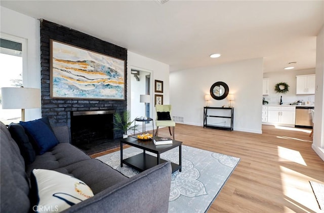 living room with a brick fireplace and light hardwood / wood-style flooring