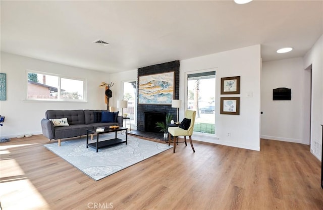 living room featuring plenty of natural light, a fireplace, and light hardwood / wood-style flooring