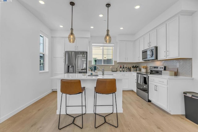 kitchen featuring stainless steel appliances, tasteful backsplash, pendant lighting, and white cabinets