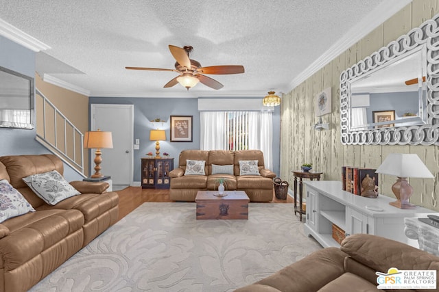 living room with ceiling fan, ornamental molding, a textured ceiling, and wood walls