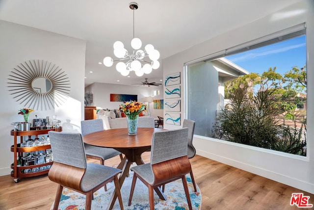 dining space featuring ceiling fan with notable chandelier and light hardwood / wood-style flooring