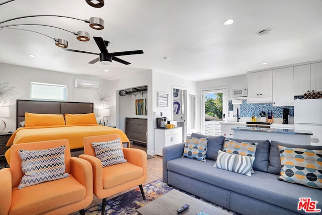 bedroom featuring sink, a wall unit AC, white fridge, ceiling fan, and light wood-type flooring