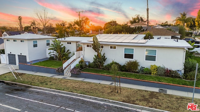 ranch-style home featuring a garage, a yard, and solar panels