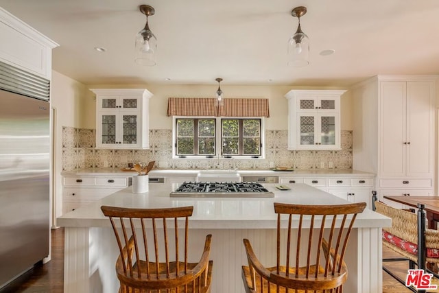 kitchen featuring white cabinetry, decorative light fixtures, a center island, appliances with stainless steel finishes, and decorative backsplash