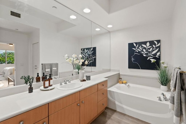 bathroom with vanity, wood-type flooring, and a tub to relax in