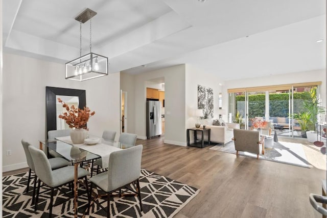 dining room featuring hardwood / wood-style floors, an inviting chandelier, and a tray ceiling