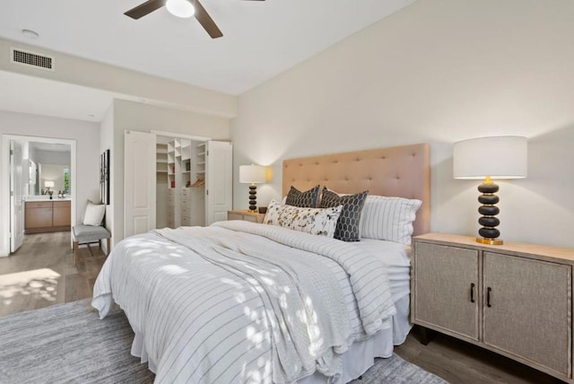 bedroom with ceiling fan, connected bathroom, and dark hardwood / wood-style floors