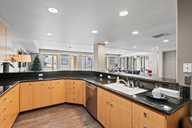 kitchen featuring sink, dark wood-type flooring, kitchen peninsula, stainless steel dishwasher, and dark stone counters